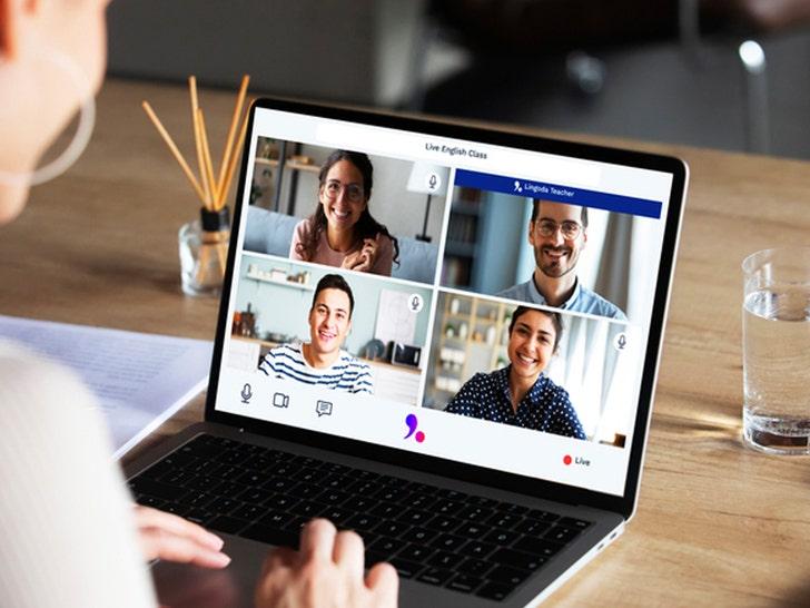A laptop displays a four-person video call while a person uses the computer at a desk, shown in soft indoor light.